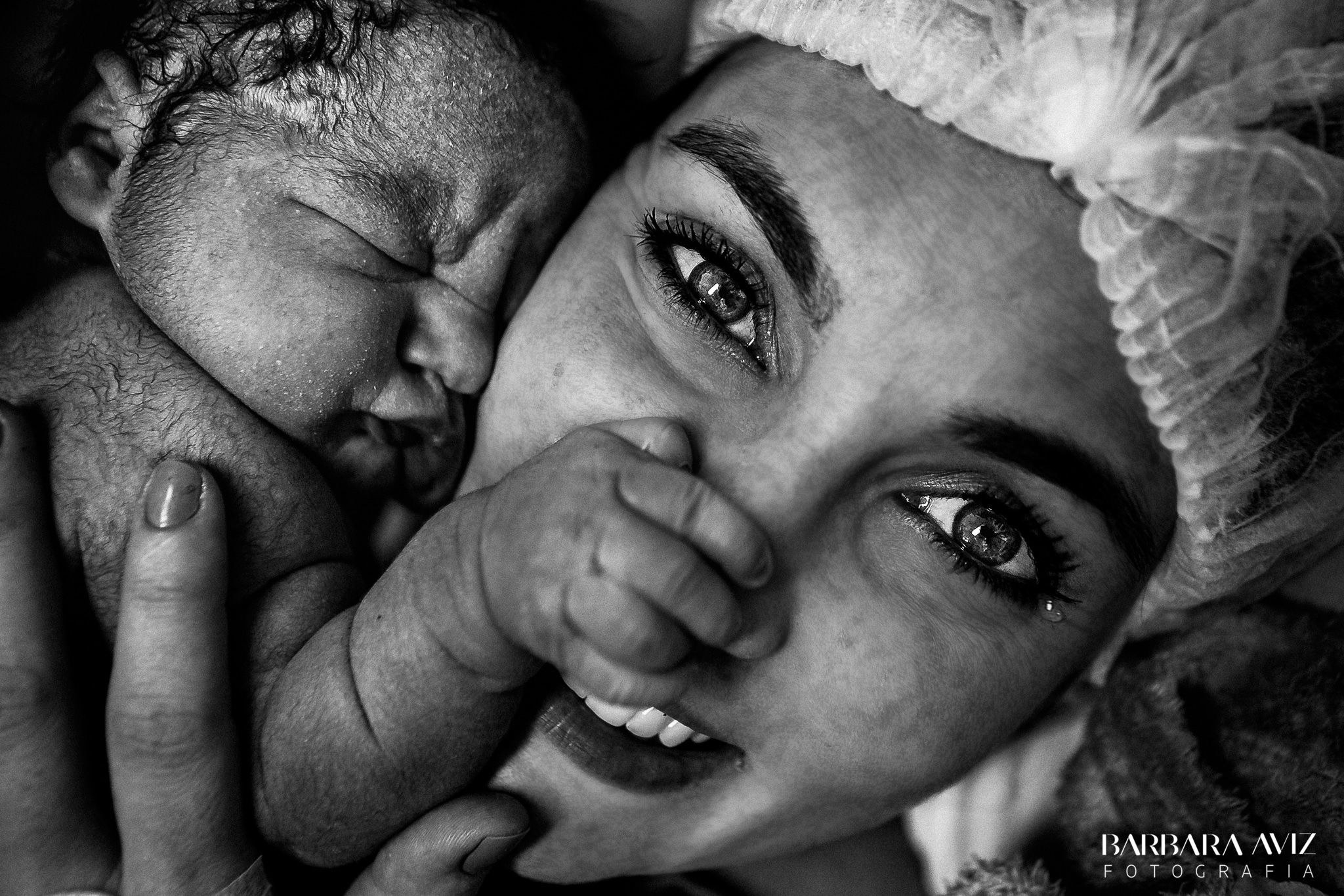 A newborn grabs his mother&#x27;s nose as she smiles for the camera