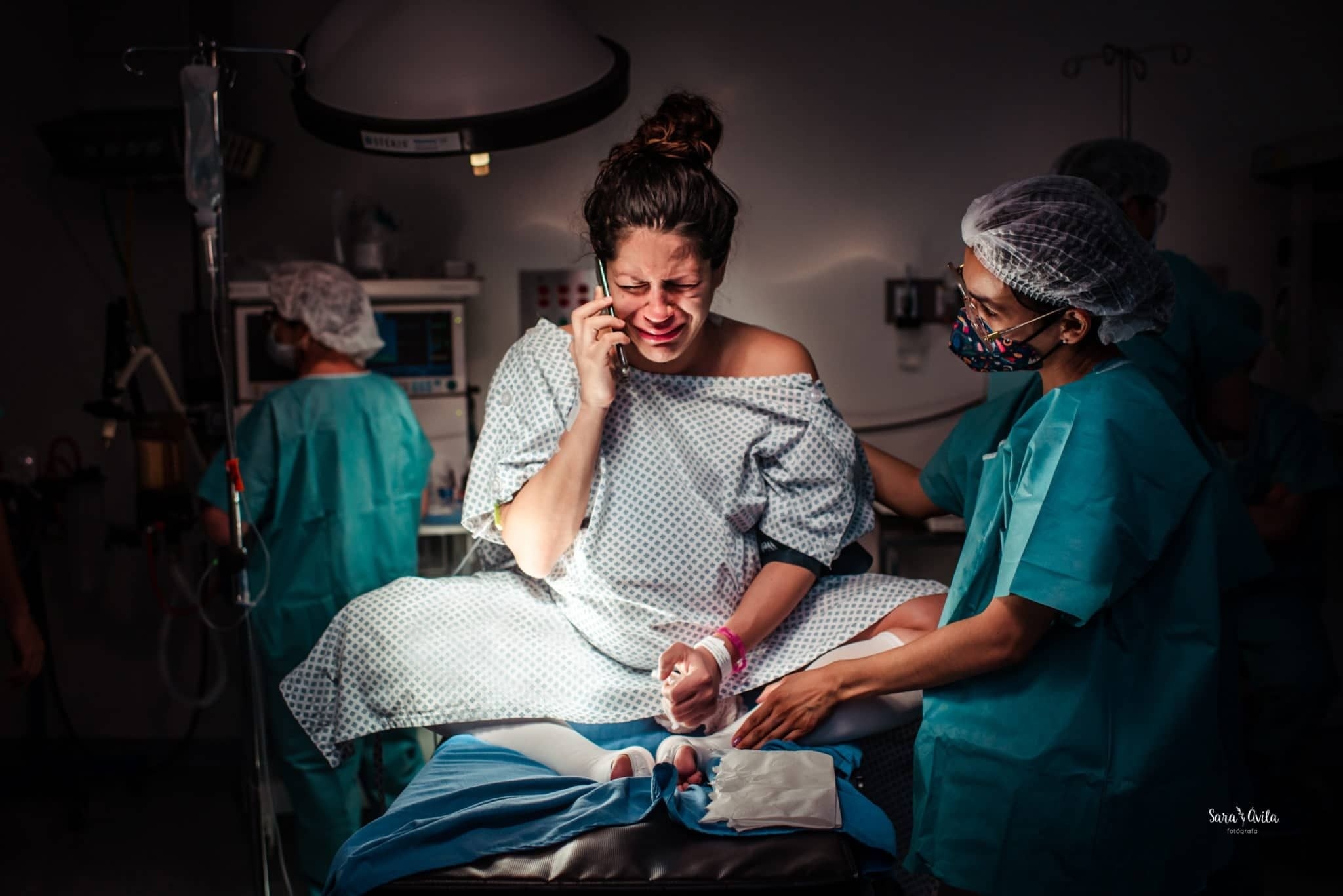 A woman in a hospital gown cries on the phone