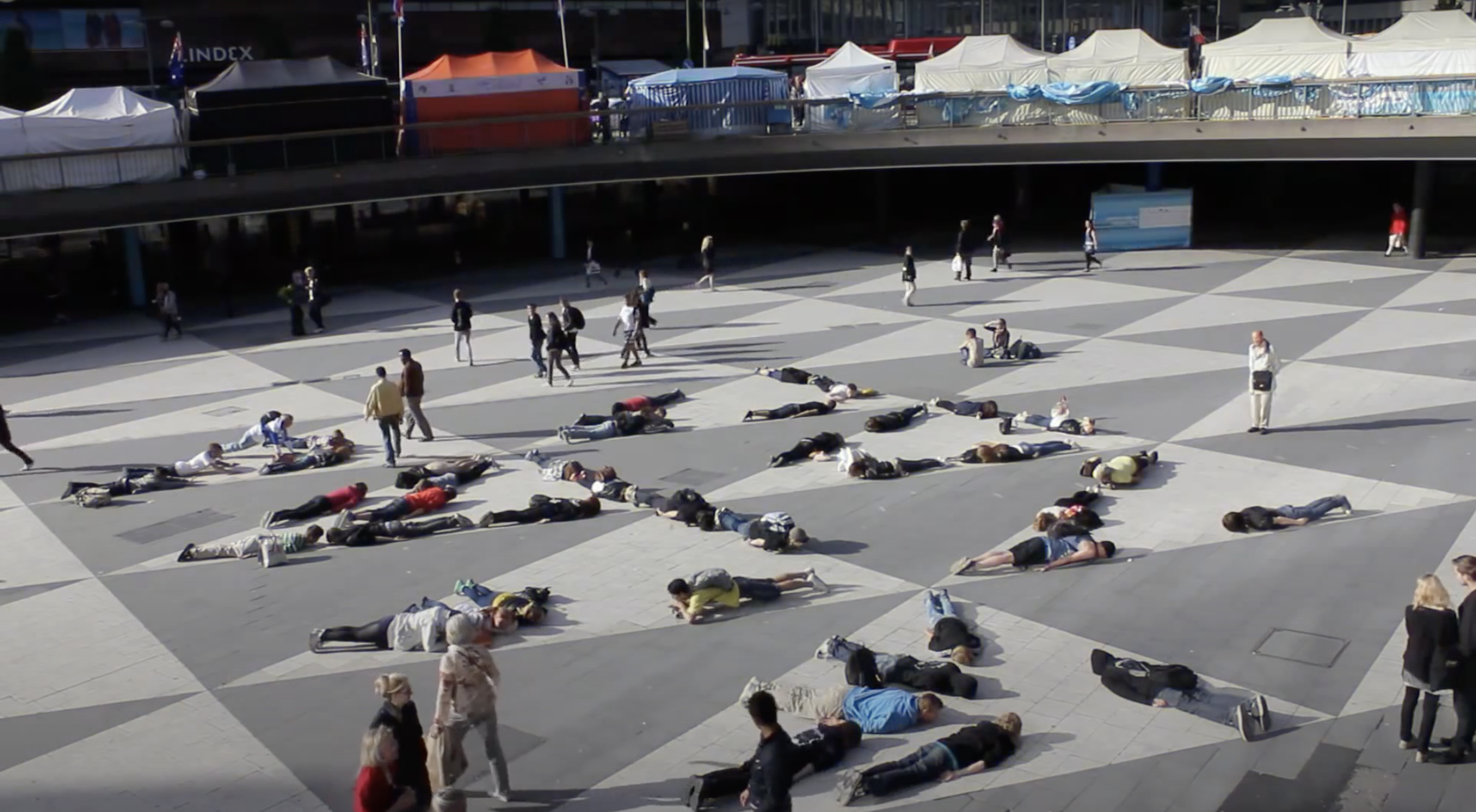 People lie down on their stomachs, or planking, as part of a flash mob