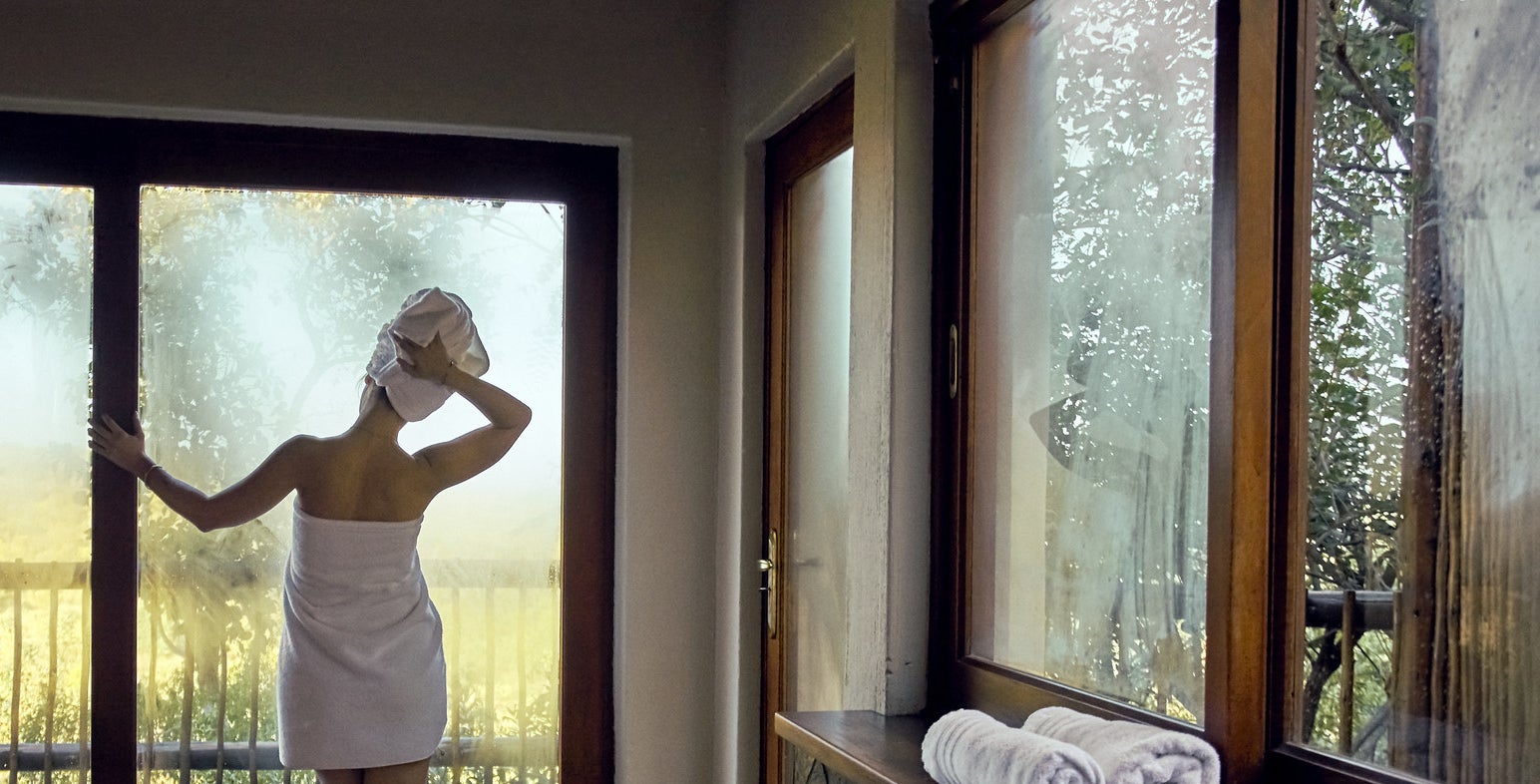 Woman wrapped in towel after bath looks out window