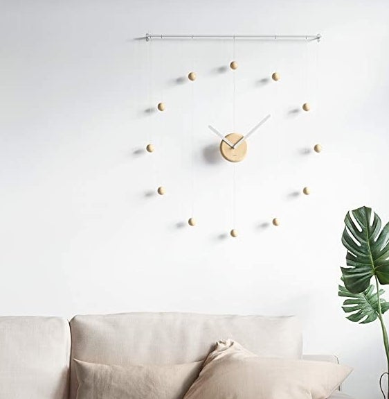 the clock hanging up on a wall above a couch and a plant in a living room