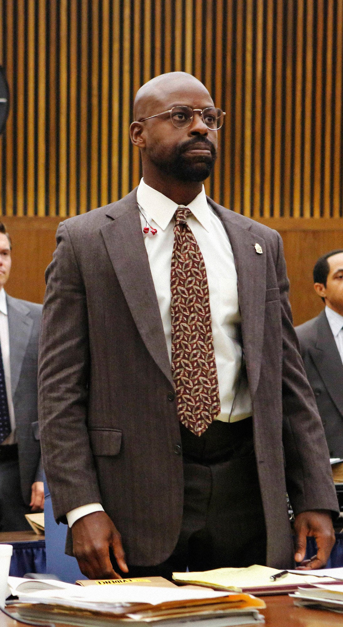 Sterling in court with a suit and thin rimmed glasses