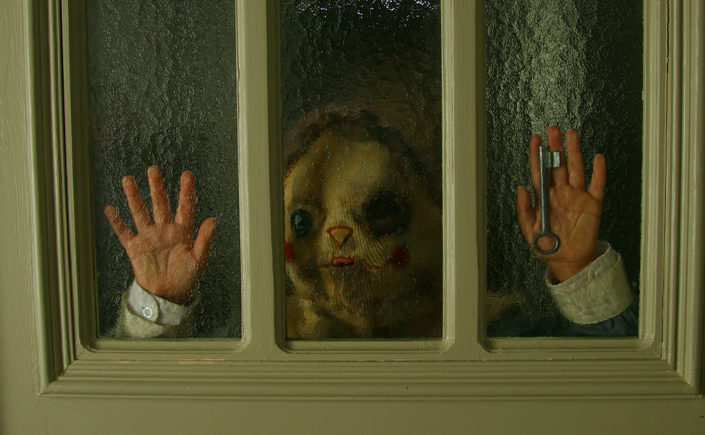 一个孩子用一块布clown-like脸握着他的手靠着门,关键在他的手中