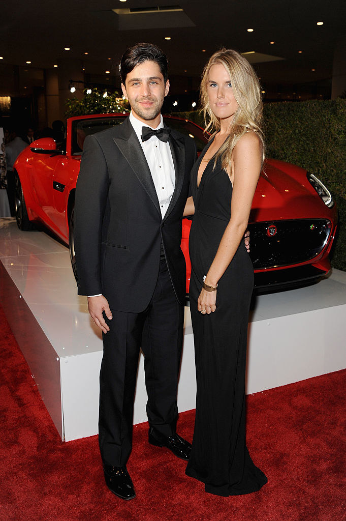 Josh and Paige posing for a photo on a red carpet in front of a convertible