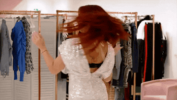 a woman twirling and smiling while trying on clothes
