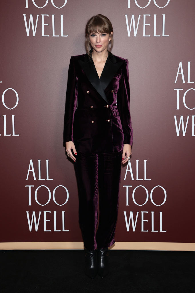 Taylor wears a tailored velvet suit with black boots