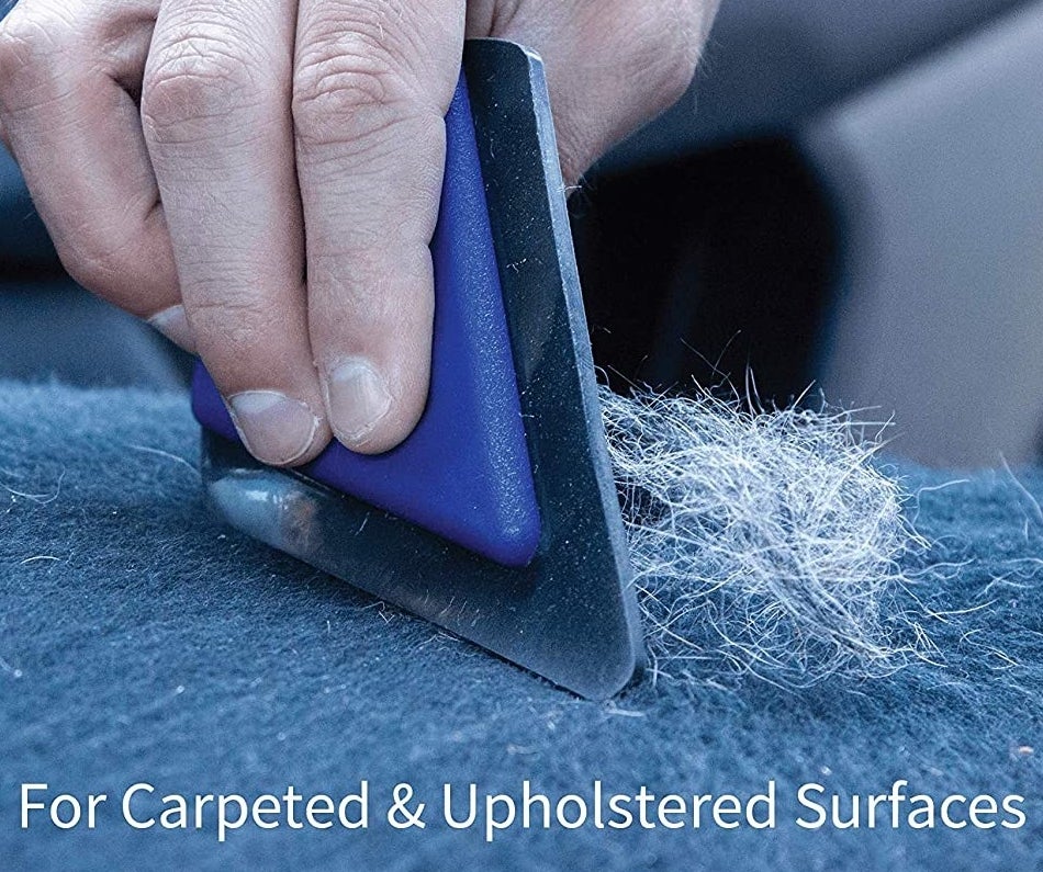 The pet hair scraper being used on a fuzzy surface