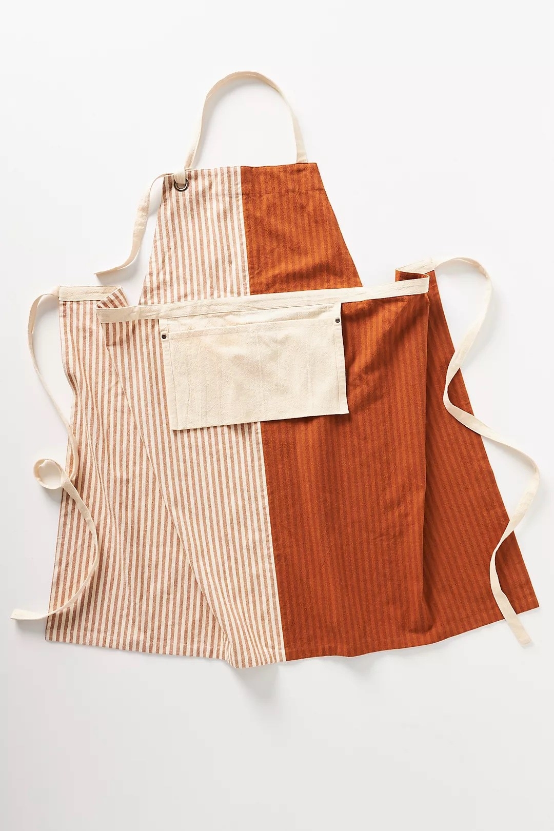 the apron with one half red and brown stripes, one half white and orange stripes and a cream pocket in the middle