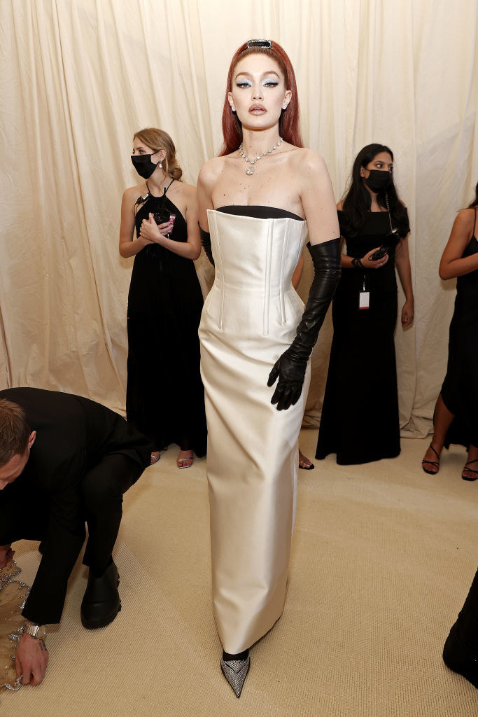 Gigi wears her hair in a high pony, an old-Hollywood style strapless dress, long gloves and pointed studded heels