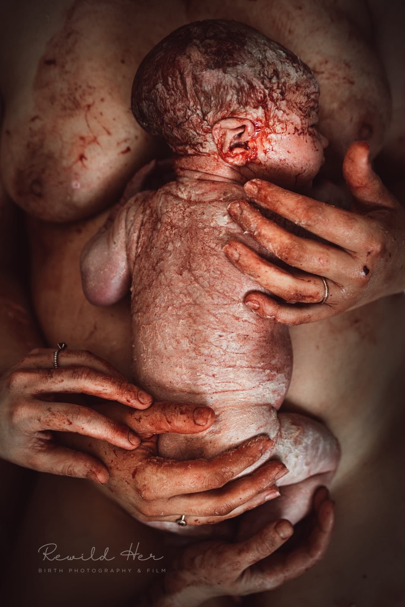 A mother holds her lightly blood covered baby to her chest
