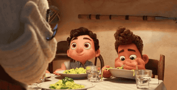Luca and Alberto gobbling down pasta while Giulia looks at them confused