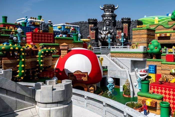 A general view of the Super Nintendo World showing a giant mushroom, plants, castles, and different levels
