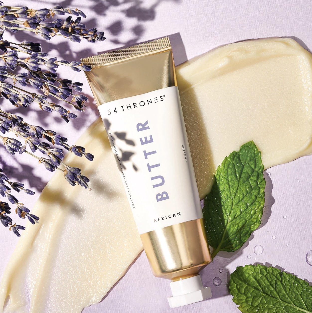 The tube of body butter over streak of the butter with lilac and mint