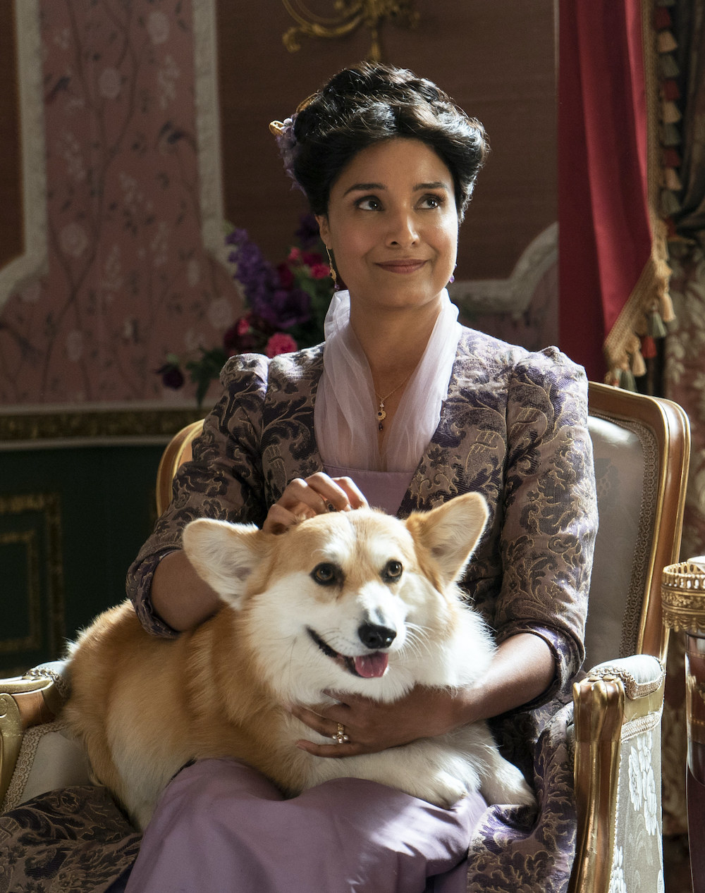 Mary sitting on a chair while petting a corgi sitting on her lap