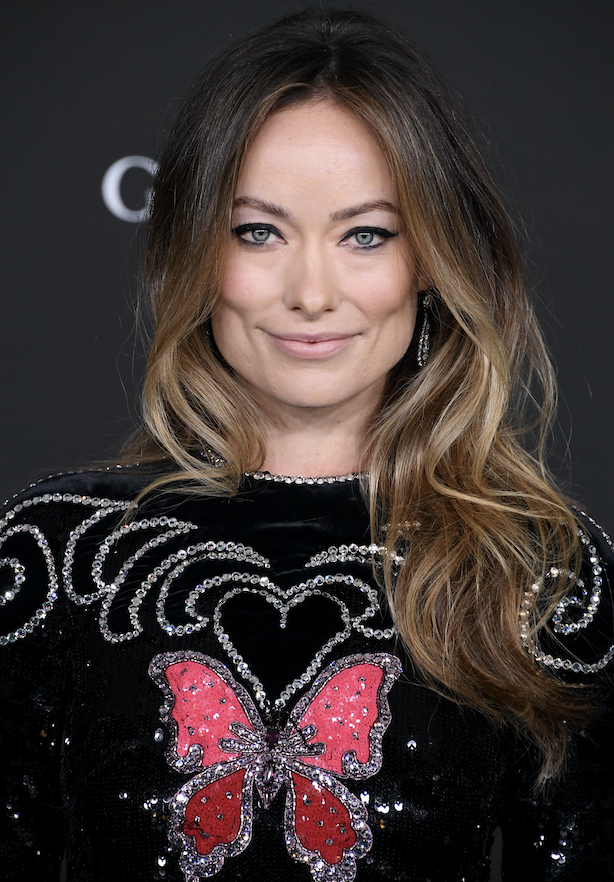 A closeup of Olivia at an event wearing a sequined outfit that features a large butterfly on the front