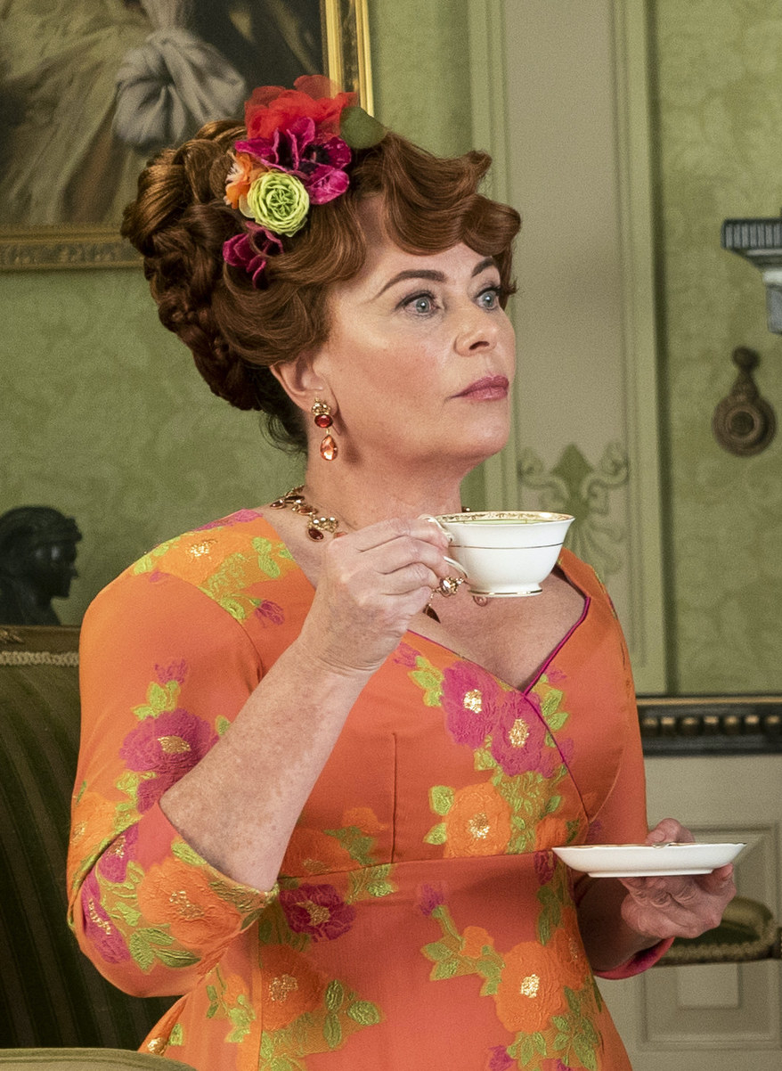 Lady Featherington holding a tea cup as she looks offscreen