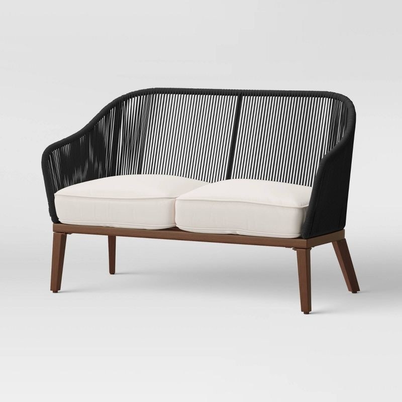 a wood patio loveseat with a black back and wooden legs