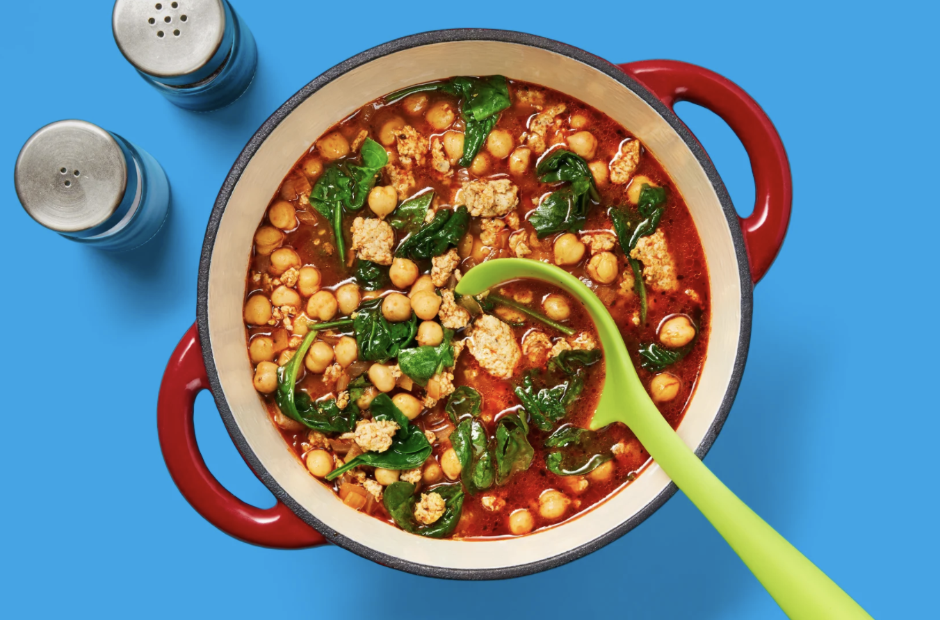 A ladle spoons out a heaping of One-Pot Chicken Sausage &amp;amp; Chickpea Soup from a large pot