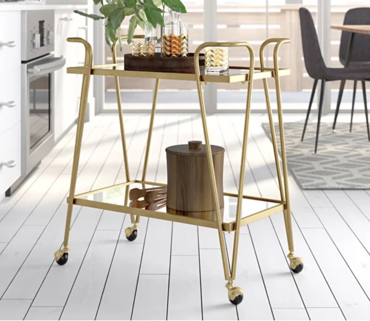The gold bar cart has two levels and various drink ware supplies