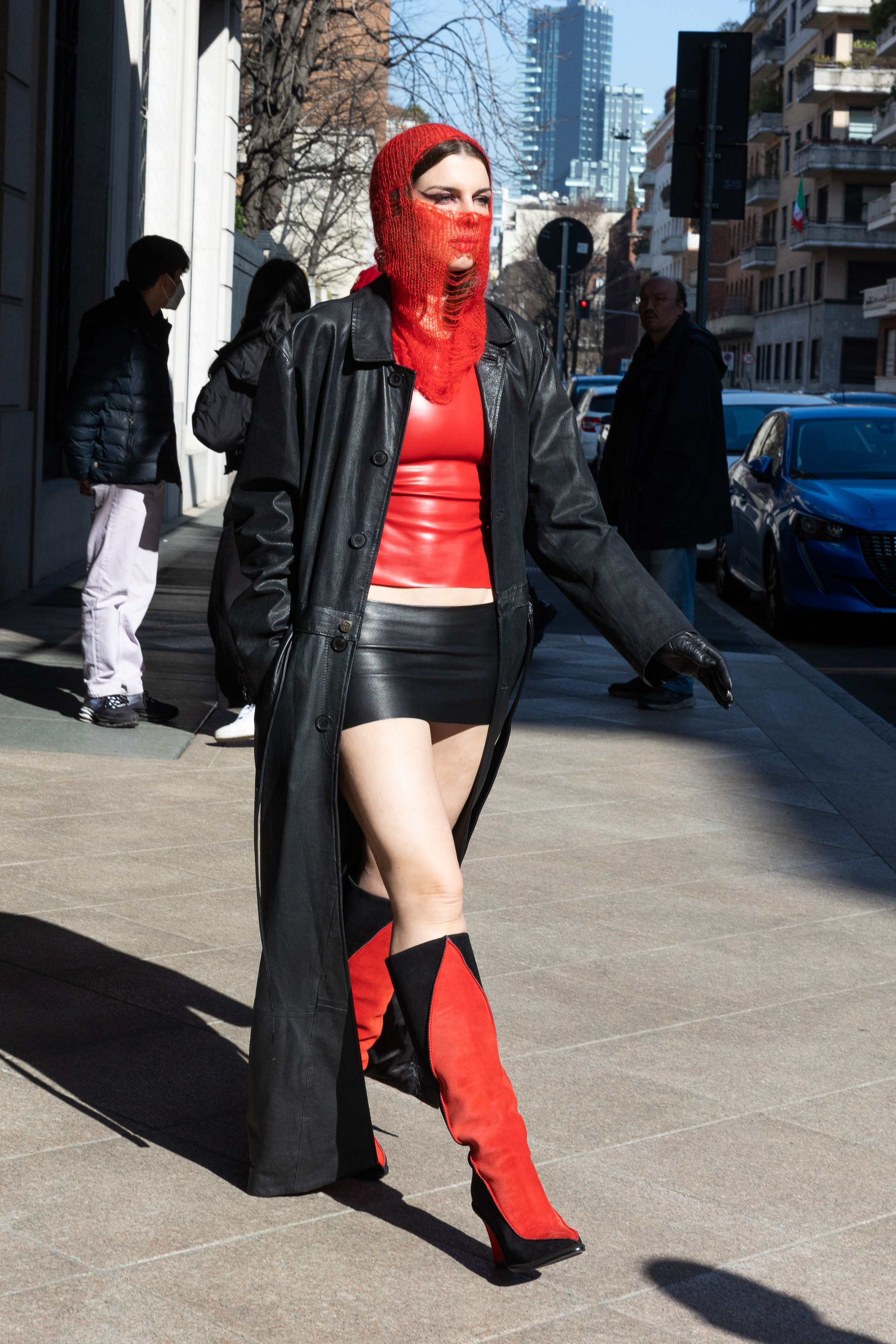 Julia wears a red leather top, black micro mini skirt and a red knit face covering