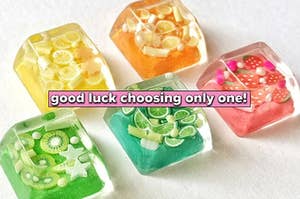 five acrylic keycaps with tiny fruits inside each one