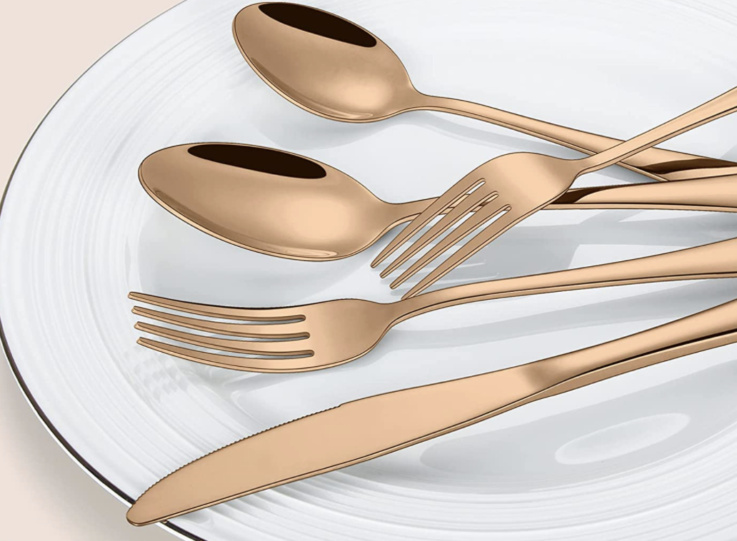 A knife, two forks, a soup spoon, and a dessert spoon on a dinner plate