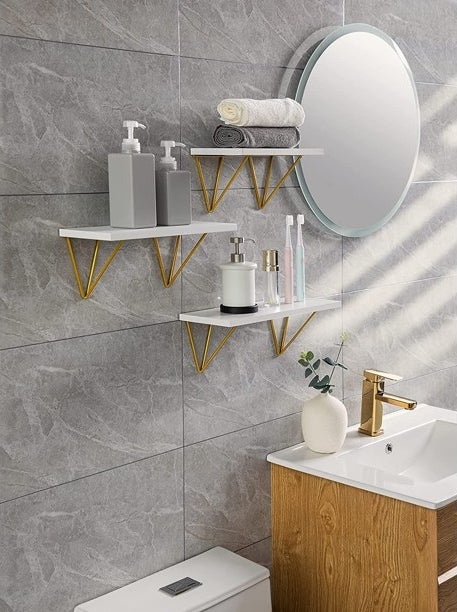 An image of a set of three wall mounted wooden shelves inside a bathroom
