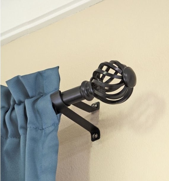 An image of a black twist cage curtain rod used to hang up a curtain panel