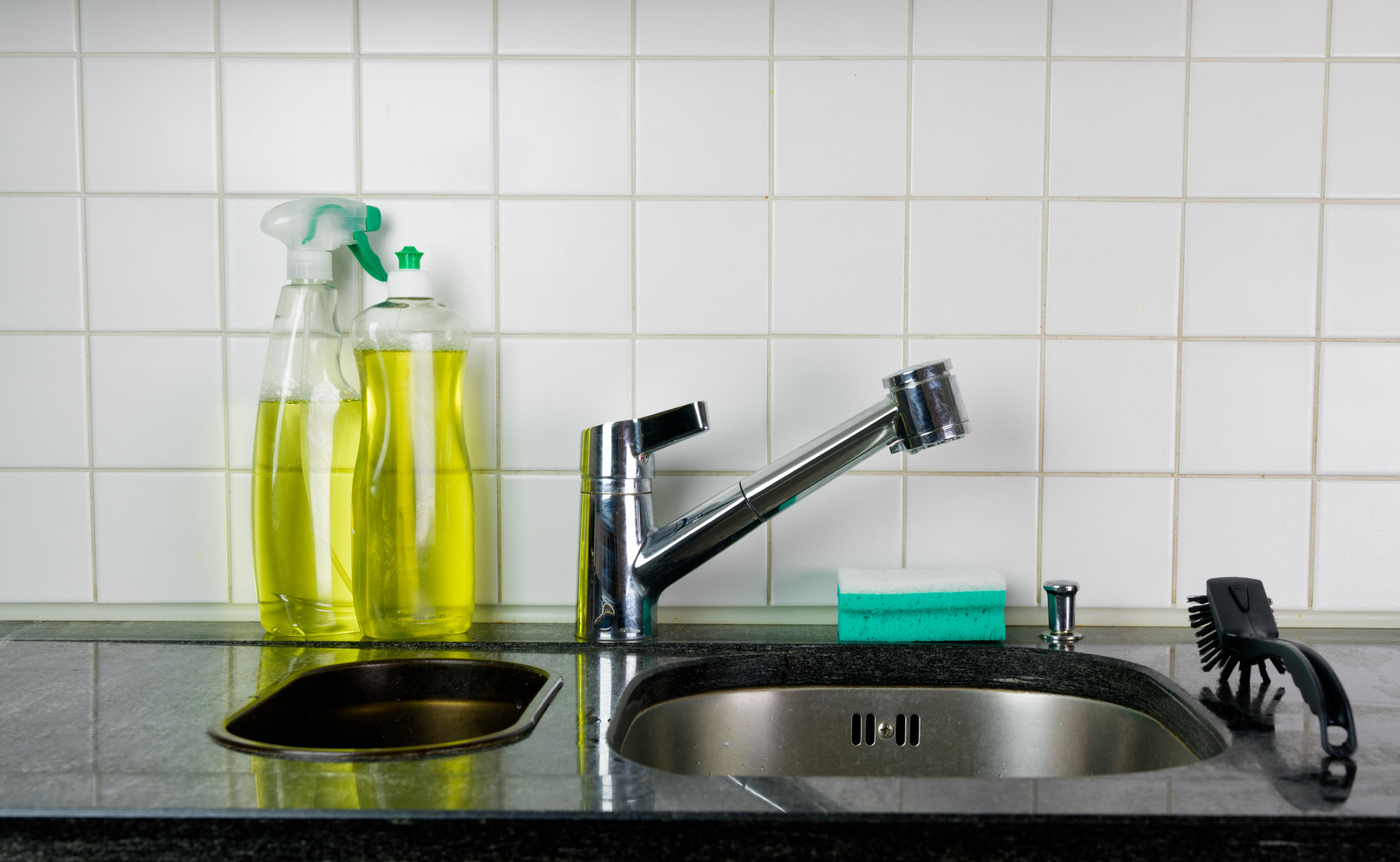 Bottles of dishwashing detergent next to a sink.