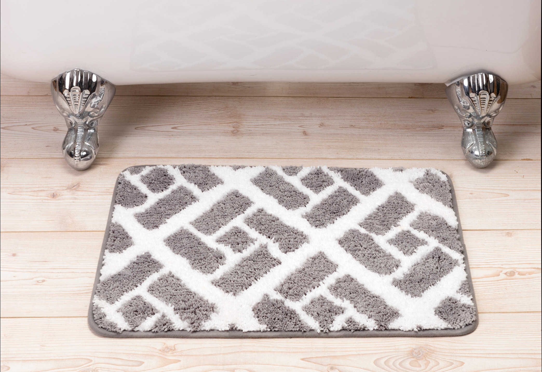 A bathmat sits on the floor in front of a tub