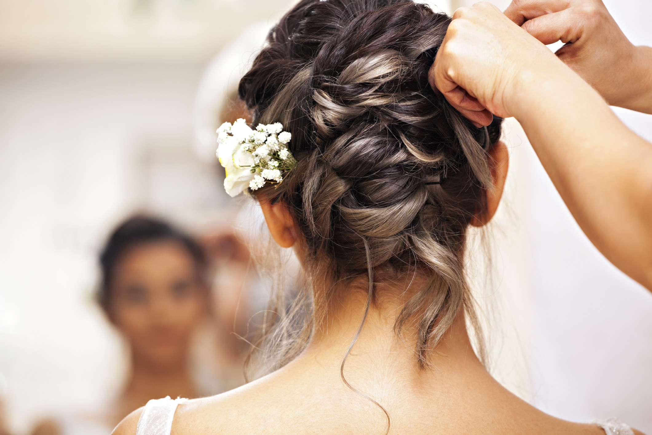 A stylist puts flowers into a bride&#x27;s hair