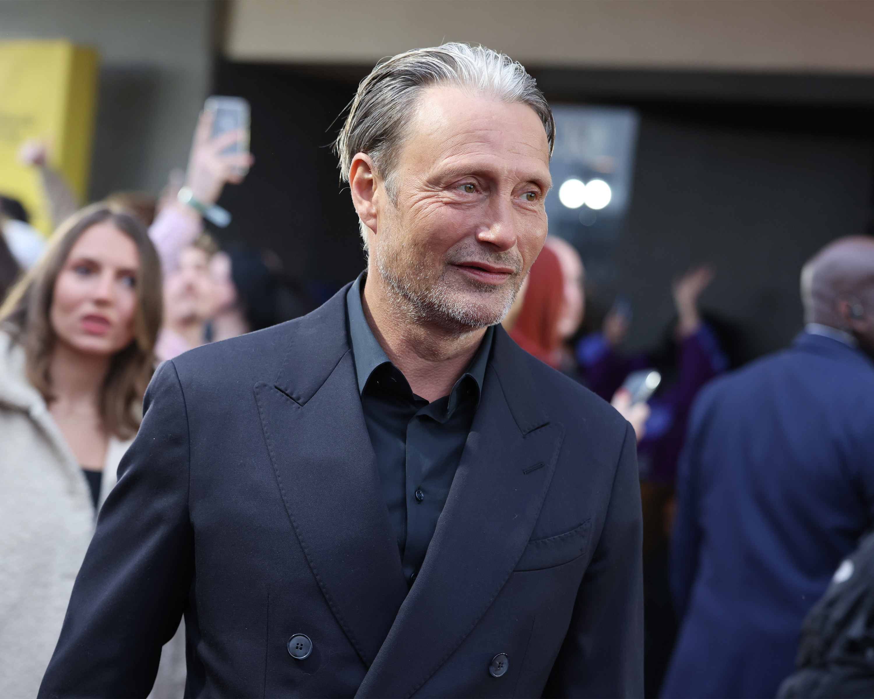 Mads smiles while wearing a suit at an event