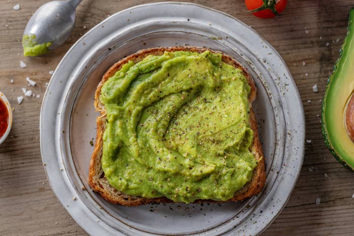 A slice of toast with avocado spread onto it