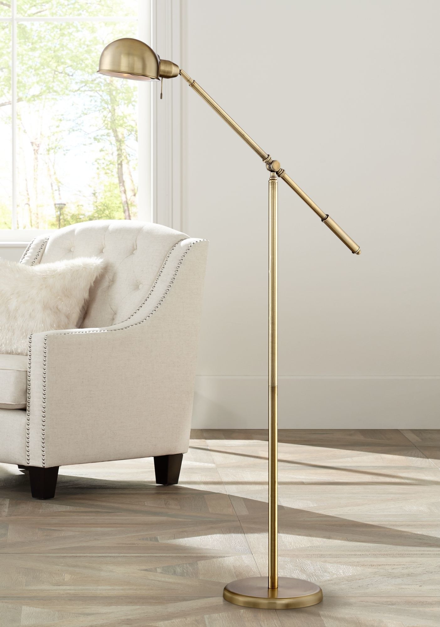 A brass pharmacy-style floor lamp with a boom-style arm that can be adjusted into any position