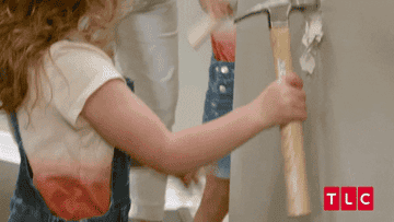 A child from the series &quot;Outdaughtered&quot; in a hardhat hammers a hole in a wall