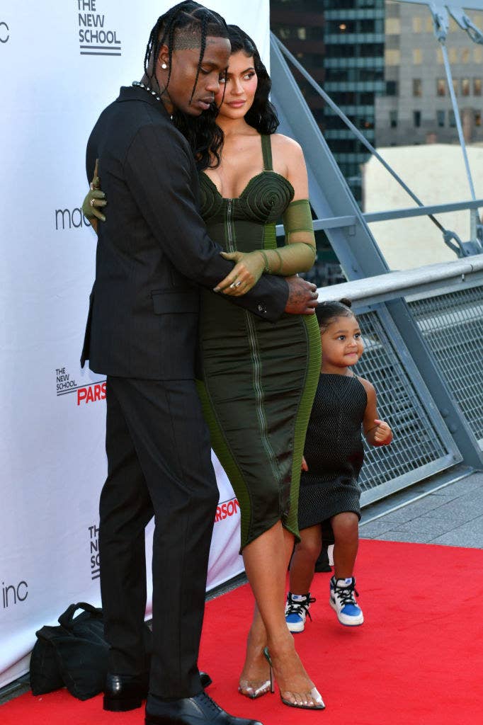 Travis and Kylie embracing on the red carpet with their daughter Stormi next to them