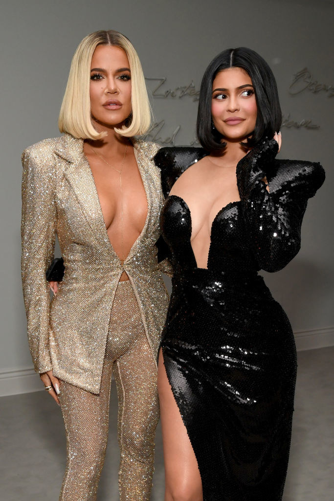 Khloé and Kylie posing for a photo together while wearing sequined outfits