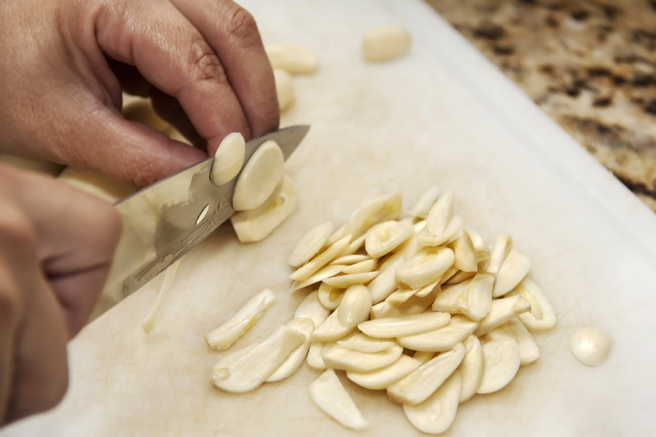 Hands slicing garlic