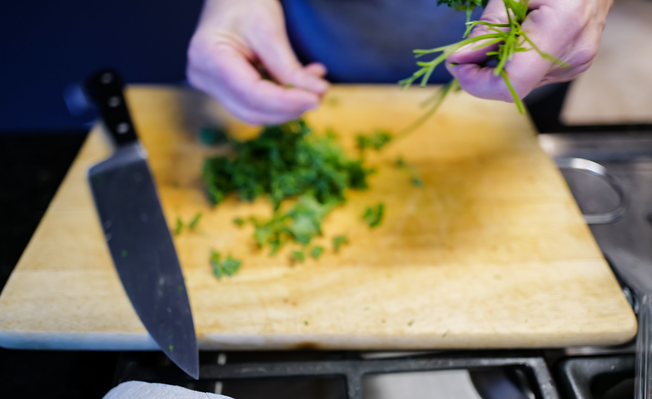 A person cutting herbs on a cutting board