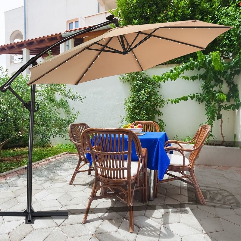 Large beige overhead umbrella with stand on a patio