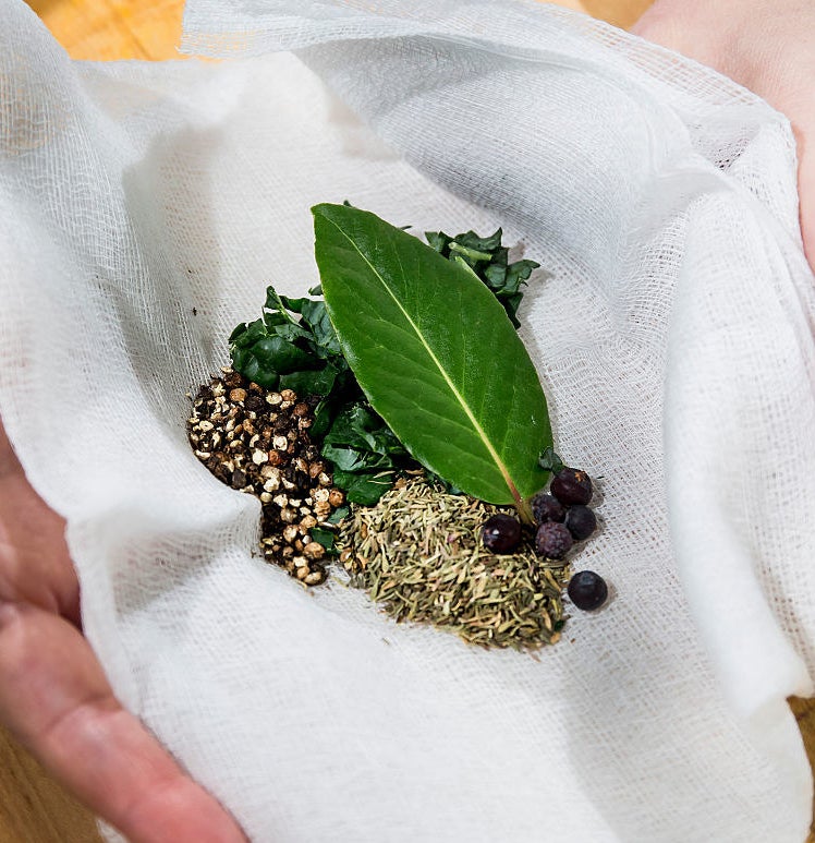 A cheese cloth with a bundle of herbs and spices inside