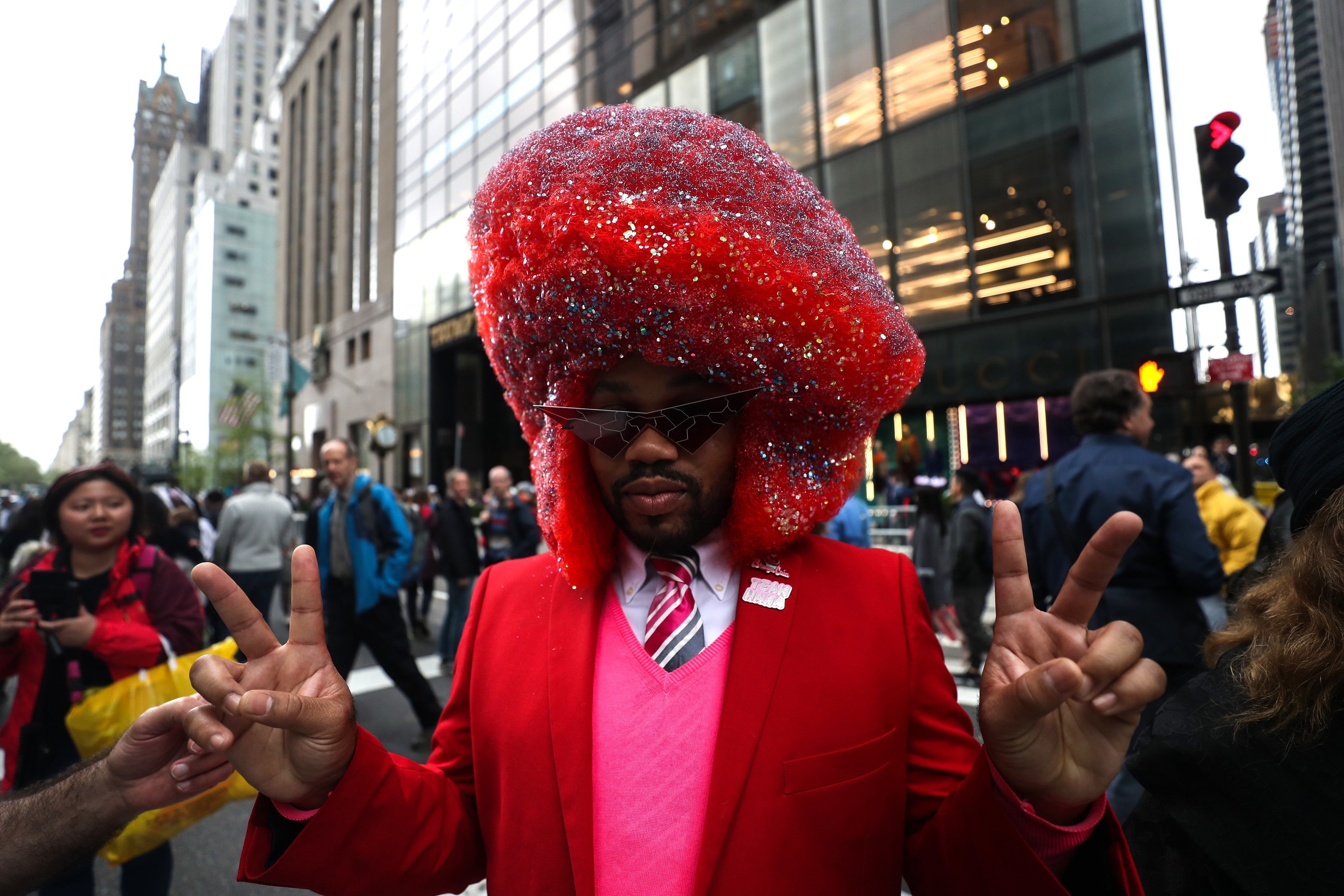 A man in a large, colorful hat gives the peace sign