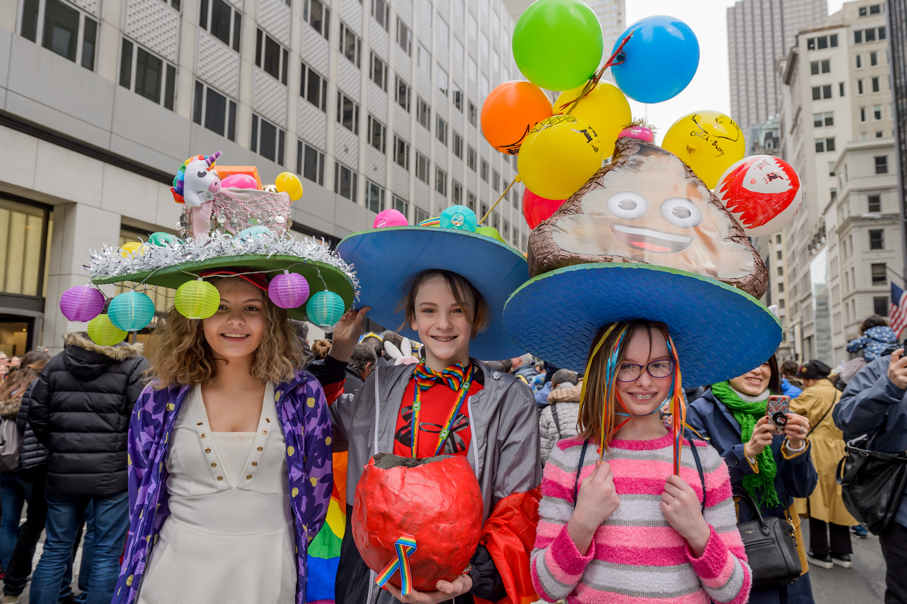 Three women in hats covered with baubles and balloons