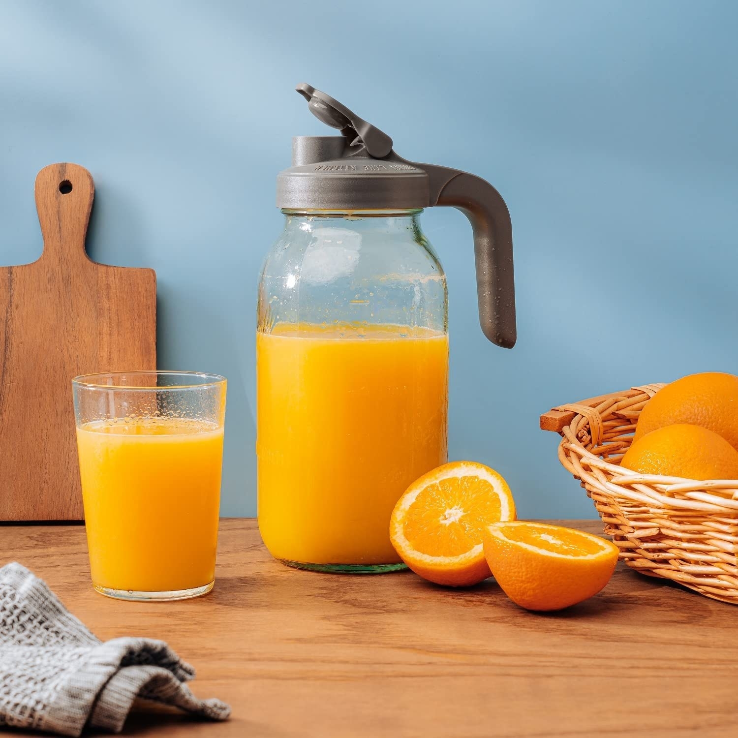 A Mason jar filled with orange juice and a glass cup beside it
