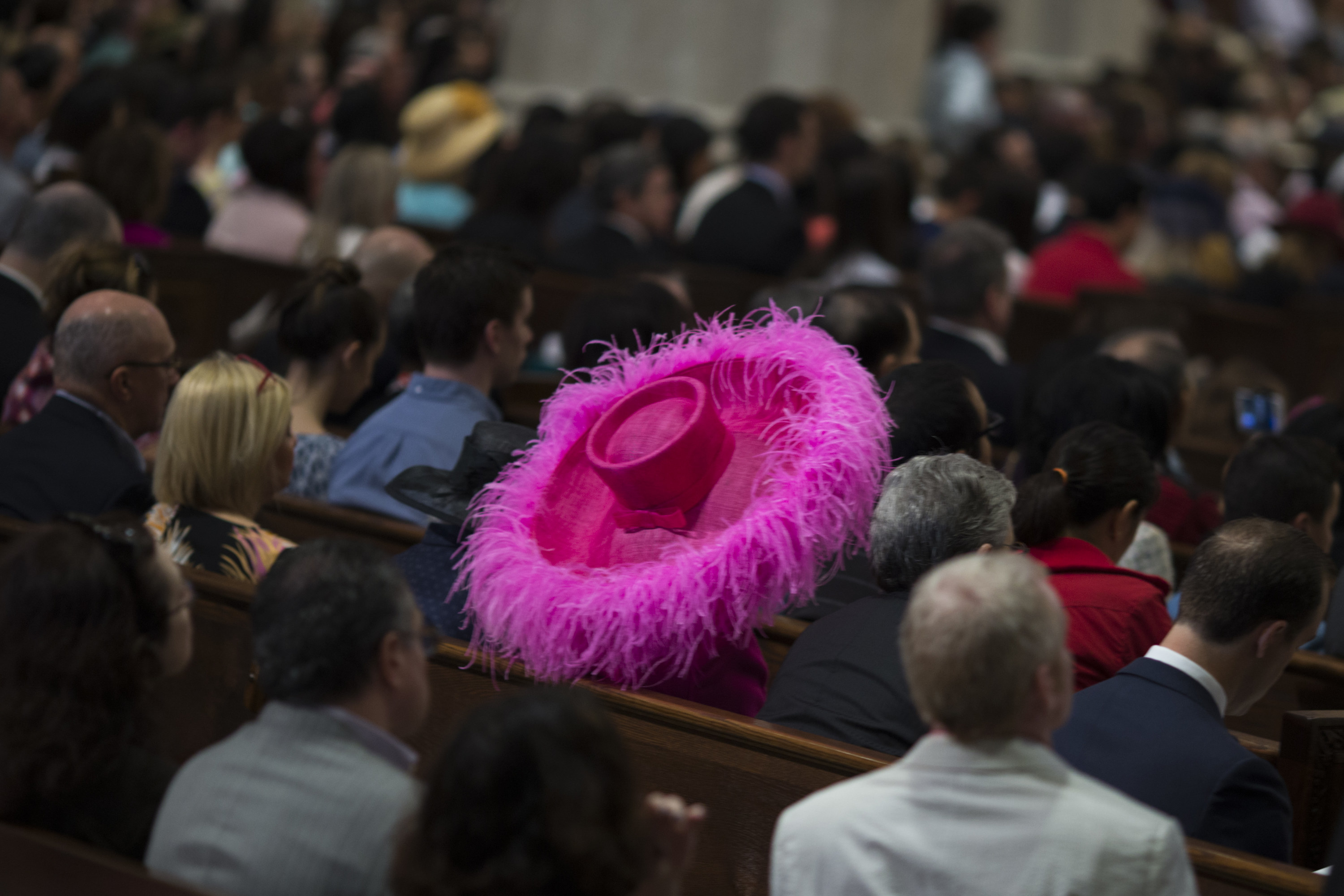A giant pink hat with pink fringe in a crowd of churchgoers