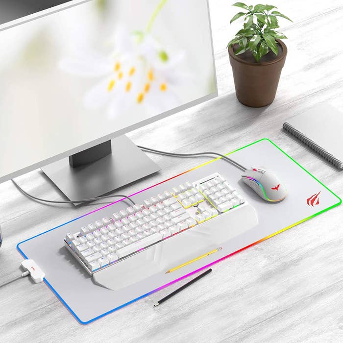 A computer with keyboard and mouse setup on the lit-up mousepad