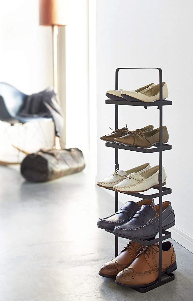 A tall shoe rack with five pairs of shoes on the shelves