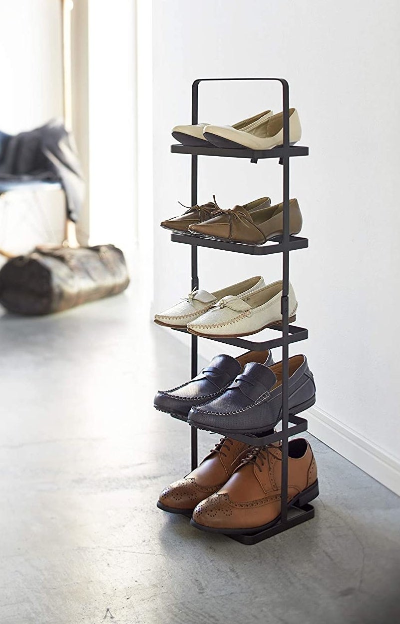 A tall shoe rack with five pairs of shoes on the shelves
