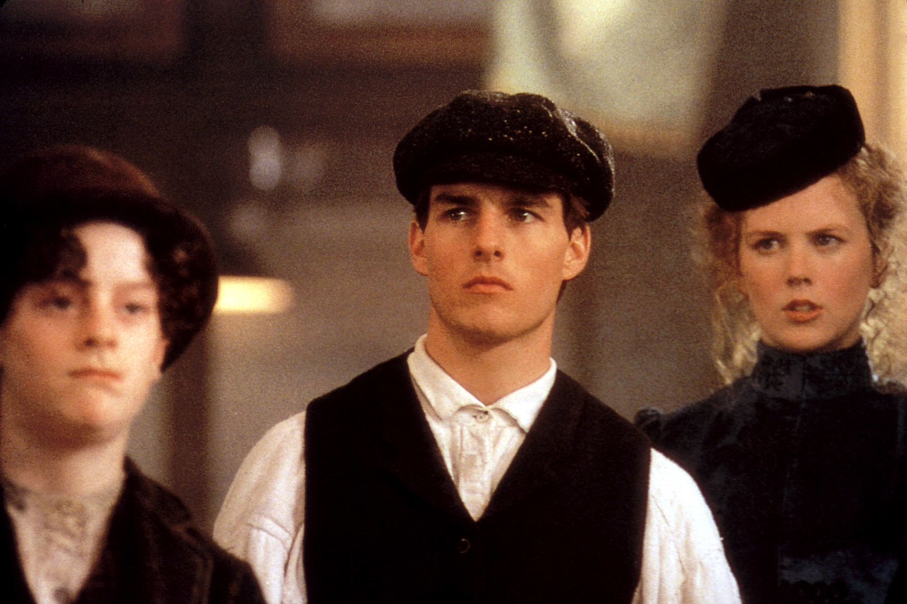 Cruise in a newsboy cap and vest with Kidman behind him and a boy in front