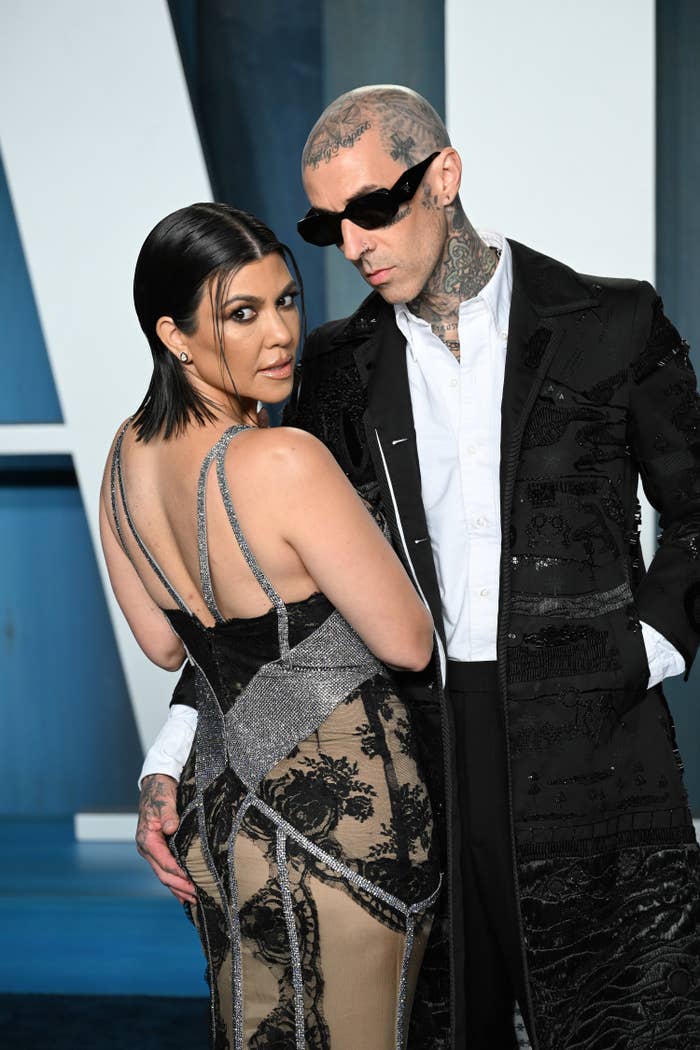 Travis poses for a photo with Kourtney while putting his hand on her butt
